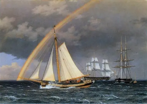 Arco iris en el mar Un yate que se cruza con algunos otros barcos